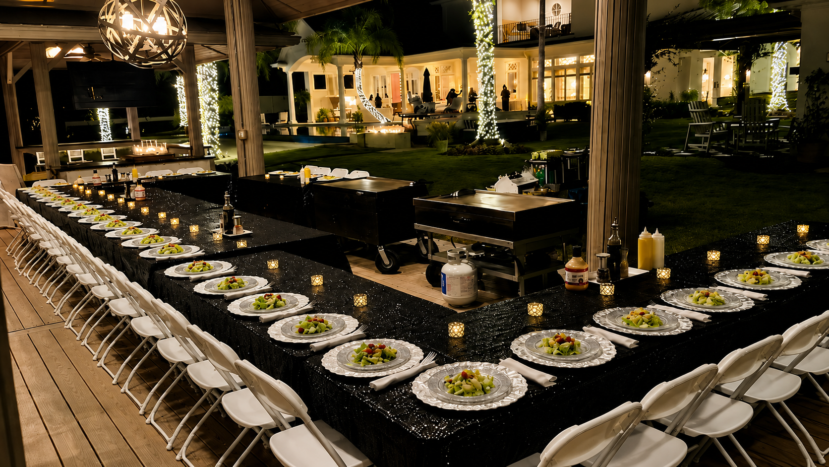 Hibachi setup on lakefront deck with twinkle lights at night